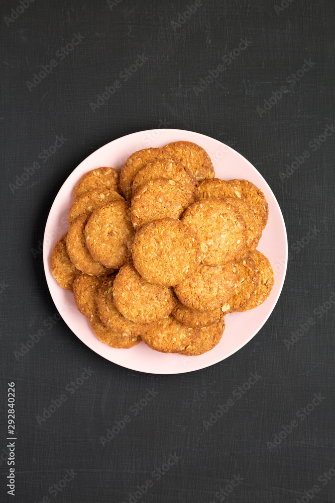 Cereal cookies on a pink plate on a black surface, overhead view. Flat lay, top view, from above. Close-up. Cereal cookies on a pink plate on a black surface, overhead view. Flat lay, top view, from above. Close-up.