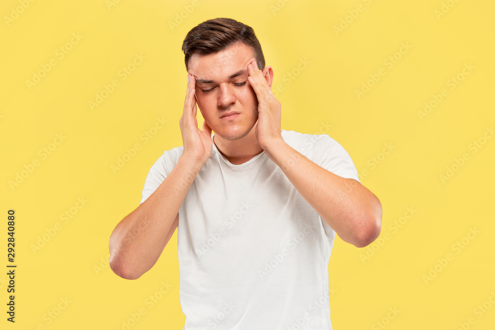 Caucasian young man's half-length portrait on yellow studio background. Beautiful male model in shirt. Concept of human emotions, facial expression, sales, ad. Suffering from headache, mental problems Caucasian young man's half-length portrait on yellow studio background. Beautiful male model in shirt. Concept of human emotions, facial expression, sales, ad. Suffering from headache, mental problems