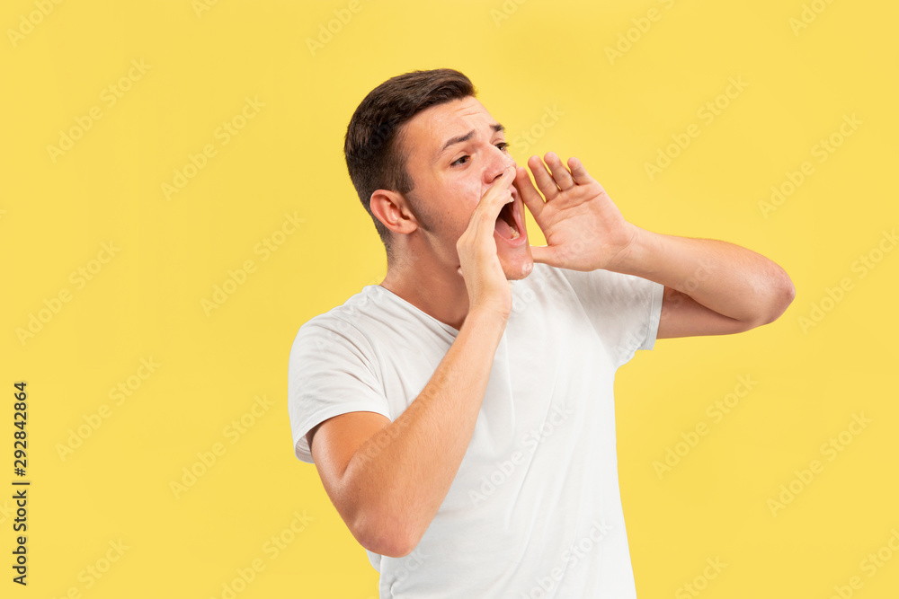 Caucasian young man's half-length portrait on yellow studio background. Beautiful male model in shirt. Concept of human emotions, facial expression, sales, ad. Calling somebody, copyspace. Caucasian young man's half-length portrait on yellow studio background. Beautiful male model in shirt. Concept of human emotions, facial expression, sales, ad. Calling somebody, copyspace.