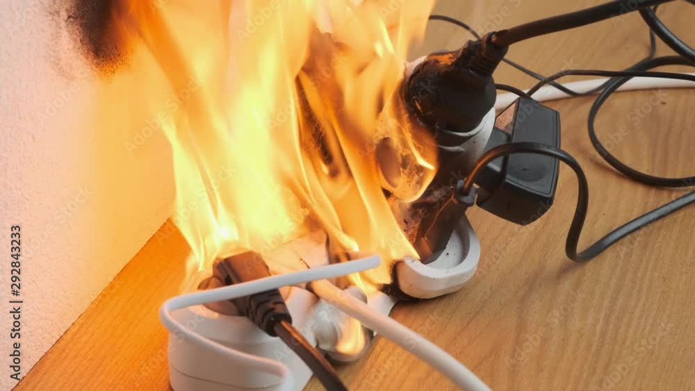 power strip with electrical plugs burns with open flame in room. concept of occurrence of fire from overload by electrical appliances.
