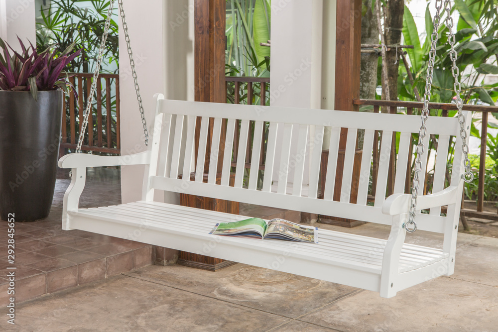 The white wood swing in the backyard. The white wood swing in the backyard.