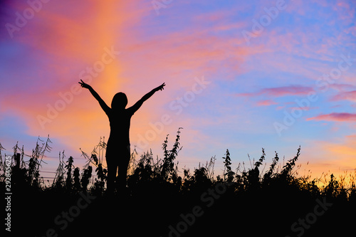 Silhouette of women with hands up Against the sunrise background © Ammak
