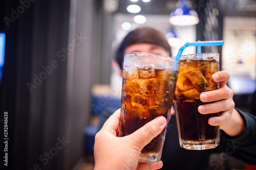 Young couple with glasses of refreshing cola with ice in restaurant, Two glasses of cola with ice
