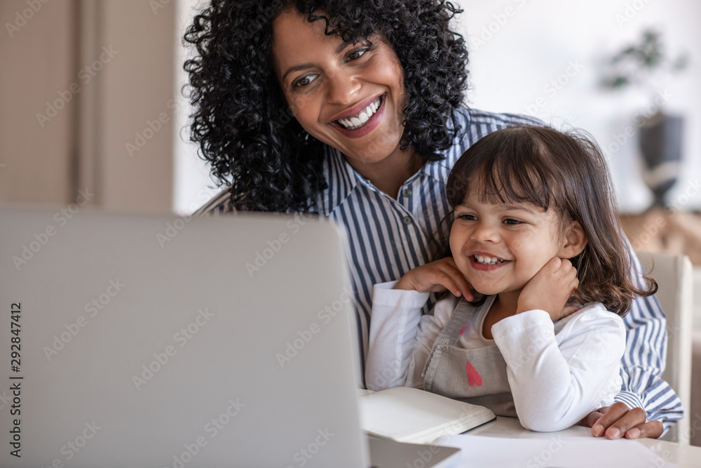 Busy mother and entrepreneur using a laptop with her daughter Busy mother and entrepreneur using a laptop with her daughter