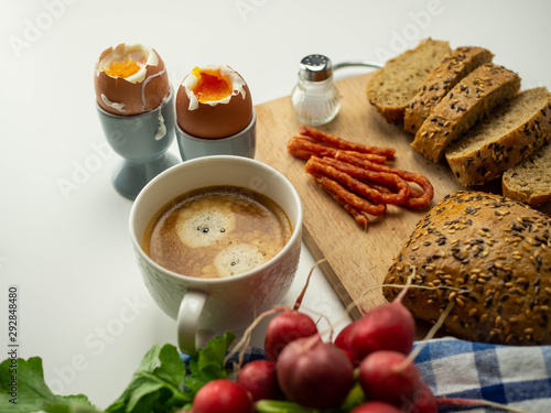 Pyszne, zdrowe śniadanie. Jajka na miękko z pieczywem, dodatkami i kawą leżące na białym tle. Widok z góry.