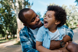 happy african american man hugging positive kid in park