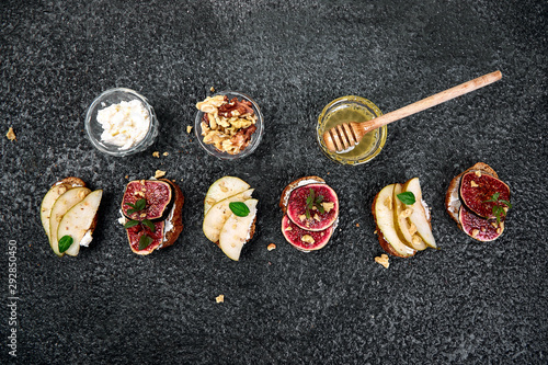 Bruschetta and Crostini with pear, ricotta cheese, honey, figs, nuts and herbs. Breakfast toasts or snack sandwiches. Antipasto. Italian food. Top view. Copy space.