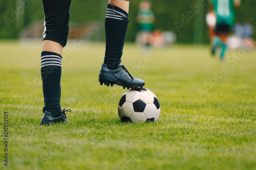 One young football player with ball on grass field. Boy in a sportswear. Player wearing black football socks and soccer cleats. Football horizontal closeup background © matimix