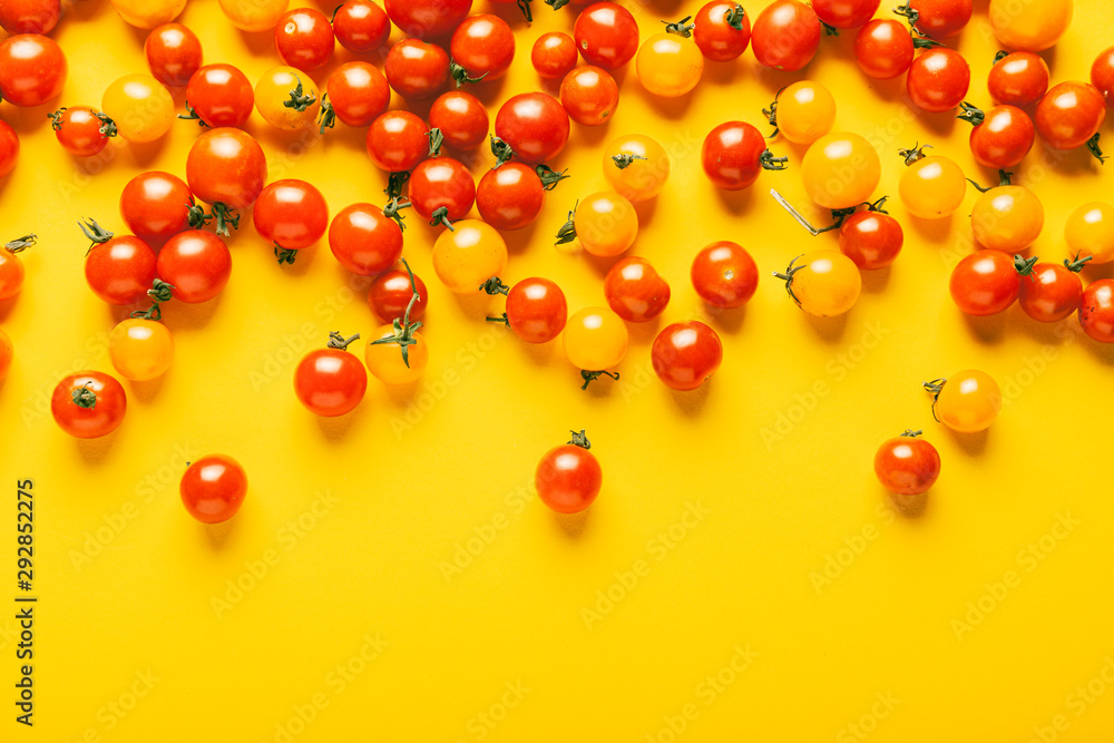 Red and yellow cherry tomatoes on yellow background. Fresh bright organic vegetables. Red and yellow cherry tomatoes on yellow background. Fresh bright organic vegetables.