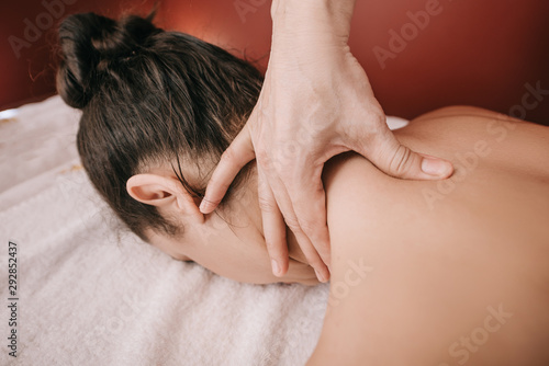 cropped view of masseur doing neck massage to woman in spa salon