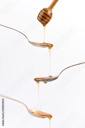 Liquid May honey flows down into spoons. Sweet cascade on a white background.