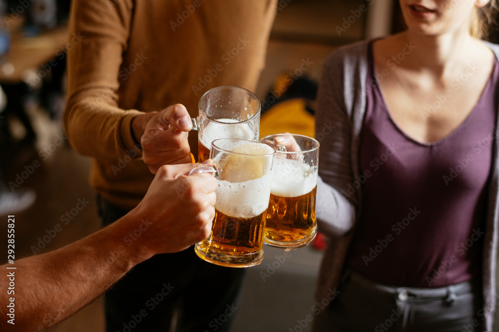 Group of happy friends drinking and toasting beer at bar 