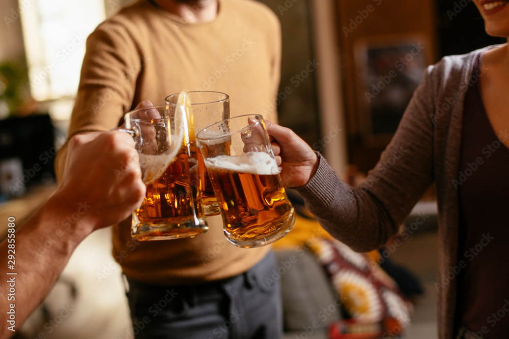 Group of happy friends drinking and toasting beer at bar 