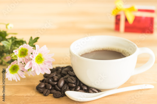 white cup of coffee with flowers on wooden background