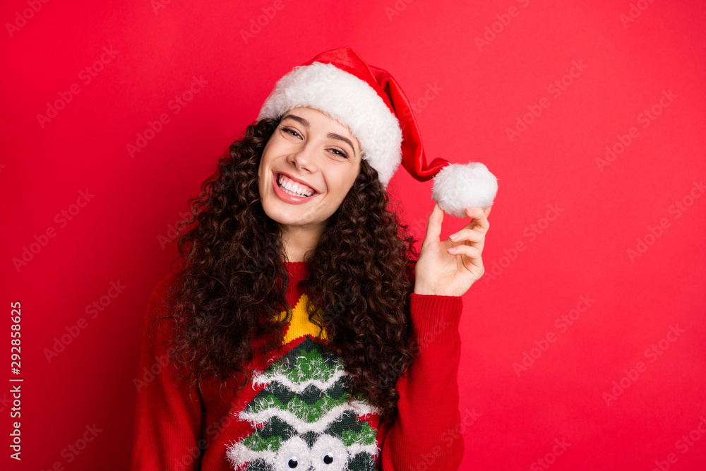 Close-up portrait of her she nice attractive lovely charming cute cheerful cheery funny wavy-haired Santa girl holding in hand hat ball isolated on bright vivid shine vibrant red color background Close-up portrait of her she nice attractive lovely charming cute cheerful cheery funny wavy-haired Santa girl holding in hand hat ball isolated on bright vivid shine vibrant red color background