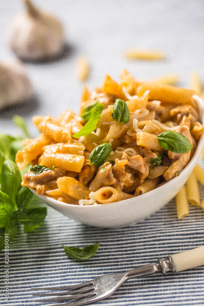 Pasta penne with chicken pieces mushrooms basil and parmesan cheese Italian food in white bowl on kitchen table Pasta penne with chicken pieces mushrooms basil and parmesan cheese Italian food in white bowl on kitchen table