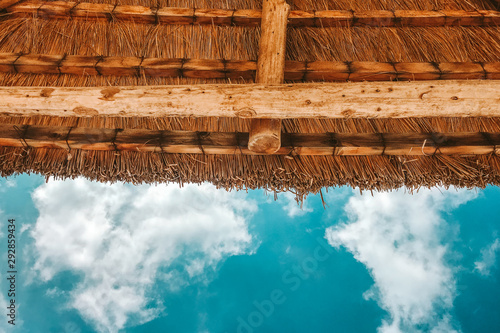 straw beach umbrella with blue sky