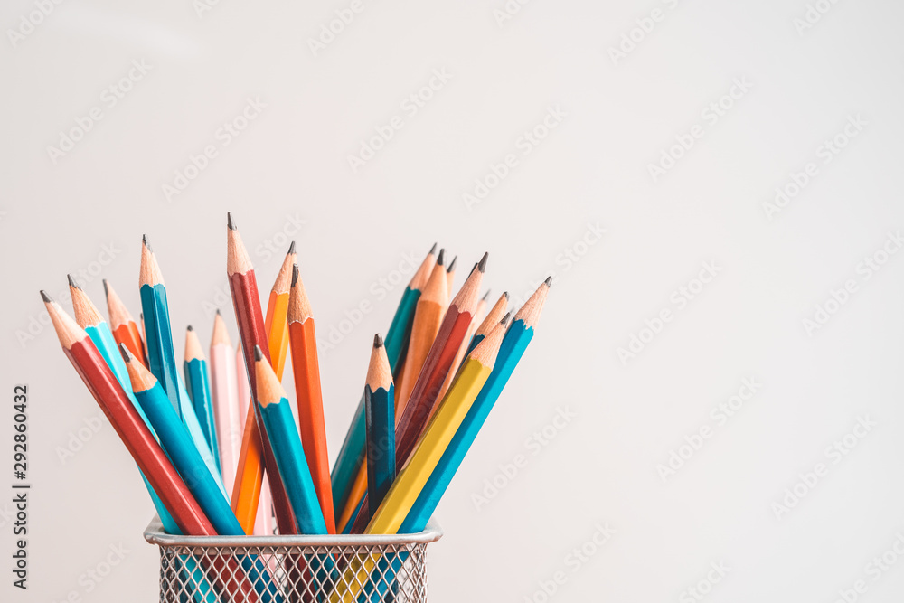 Colored pencils in box placed on wooden table on white background