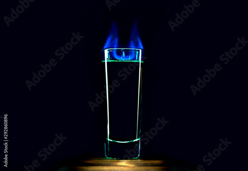 Burning alcoholic drink in a glass on a black background. Shot of absinthe with devil horns, alcohol addiction concept. Alcoholic beverages danger. photo