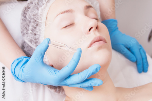 Cosmetic ampoule  a woman in the beauty salon. Vitamin in cosmetic ampoule. Hyaluronic acid.