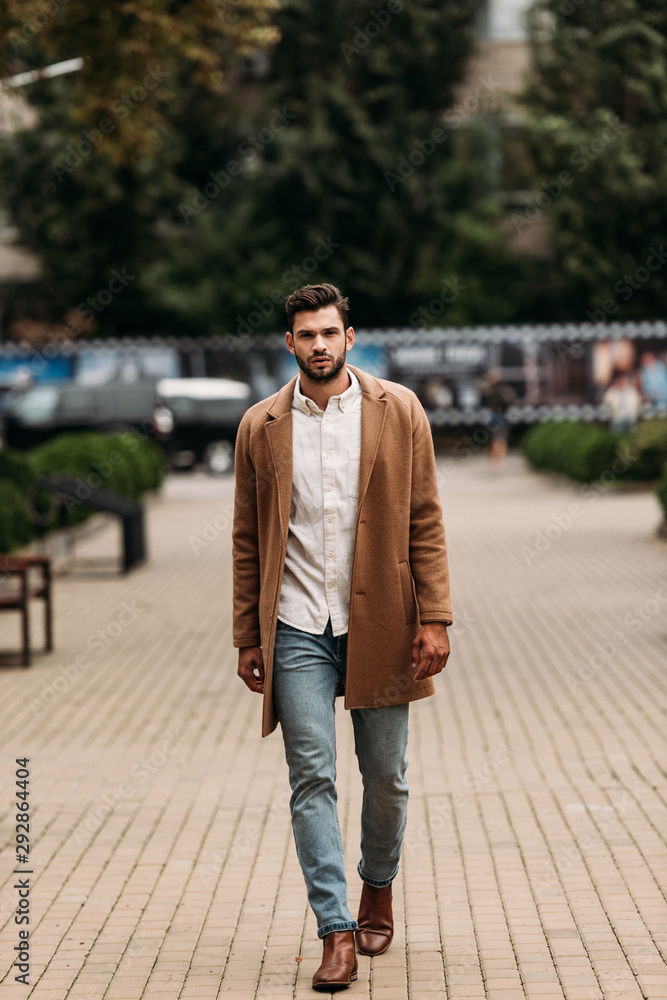 full length view of handsome bearded man in stylish coat in autumn day on street full length view of handsome bearded man in stylish coat in autumn day on street