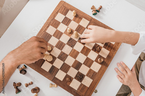 cropped view of dad and son playing chess together at home