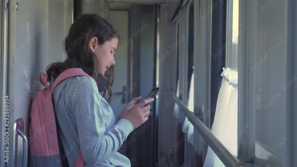 little girl walks on a train compartment car with a backpack and a smartphone. travel transportation railroad concept. the girl in the train lifestyle at the window corresponds the girl in the train little girl walks on a train compartment car with a backpack and a smartphone. travel transportation railroad concept. the girl in the train lifestyle at the window corresponds the girl in the train