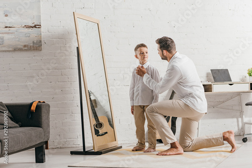 father helping son to get dressed near mirror