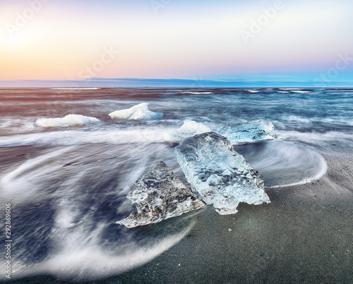 Incredible pieces of the iceberg sparkle on famous Diamond Beach at  Jokulsarlon lagoon during sunset © pilat666