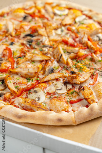 Hot chicken pizza with mushrooms and bell pepper with a thick crust in a delivery box