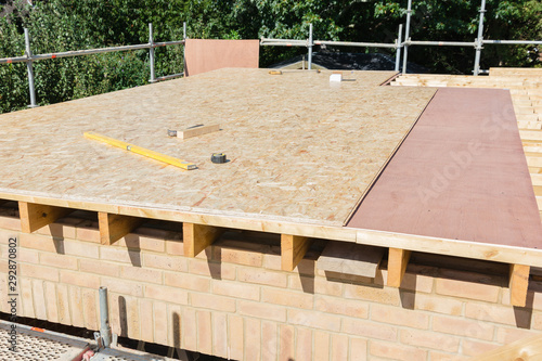 Renovation projects. Building of extension of the existing house, unfinished wooden roof structure, brick walls, view from scaffoliding, selective focus