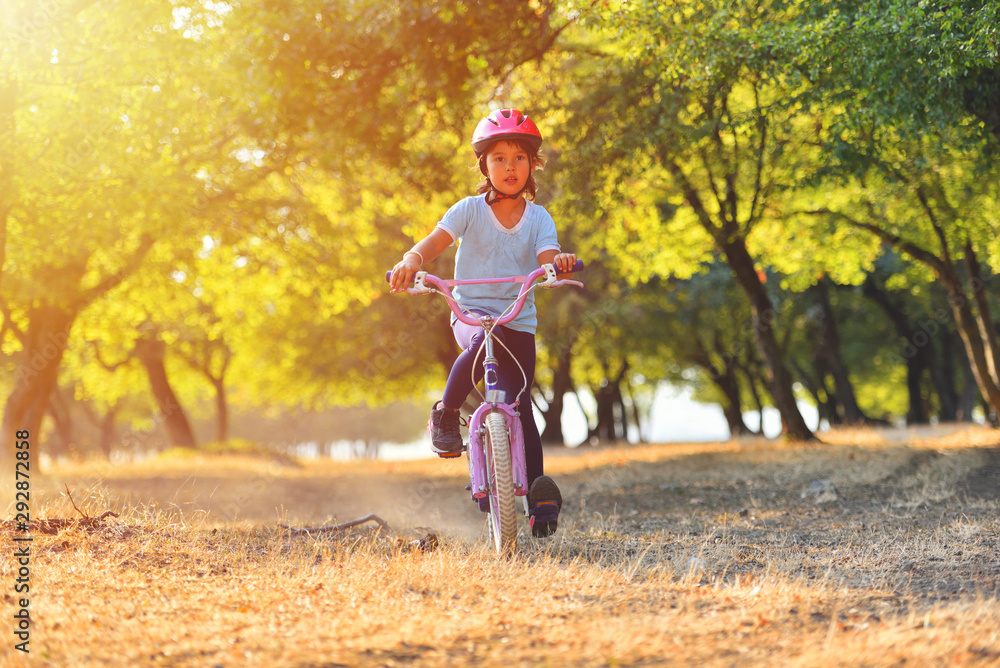 Happy kid girl of 7 years having fun in autumn park with a bicycle on beautiful fall day. Active child wearing bike helmet Happy kid girl of 7 years having fun in autumn park with a bicycle on beautiful fall day. Active child wearing bike helmet