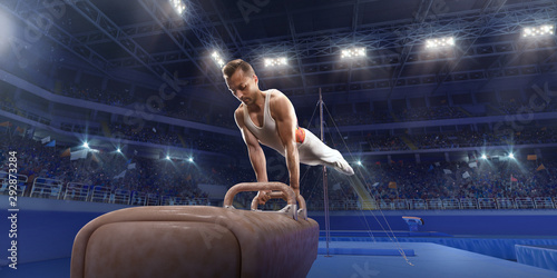 Male athlete doing a complicated exciting trick on a Pommel horse in a professional gym. Man perform stunt in bright sports clothes