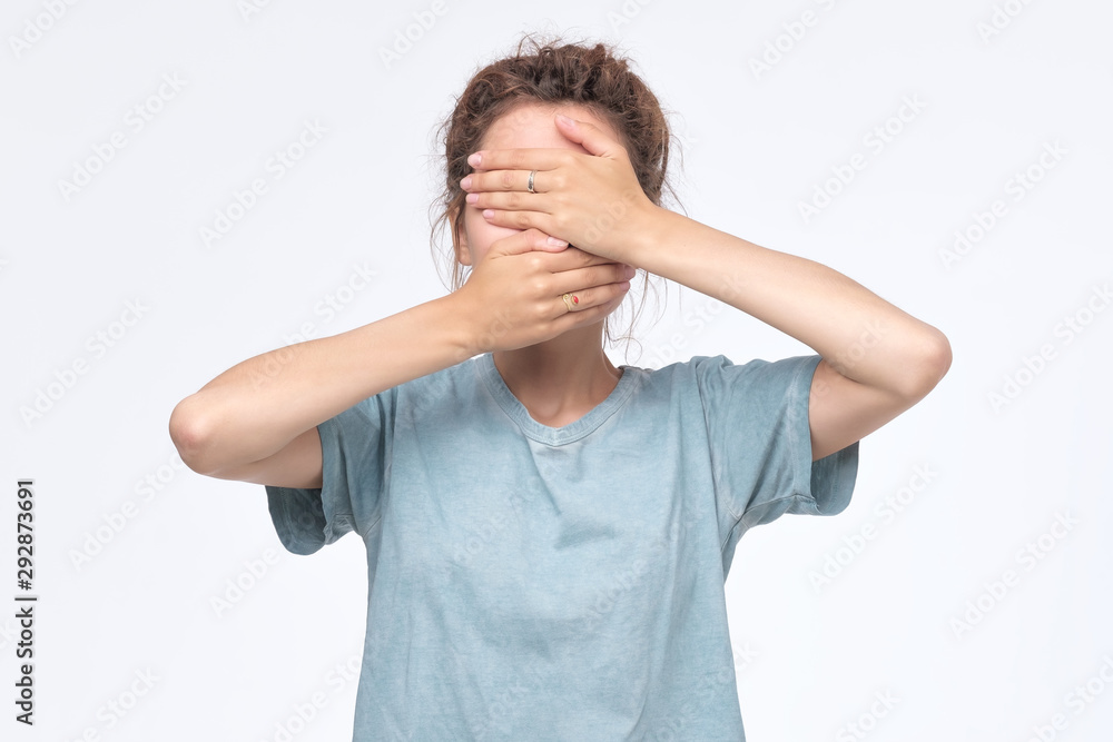 young woman in blue t-shirt covering face with hands young woman in blue t-shirt covering face with hands