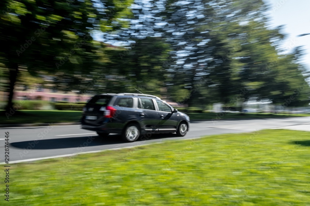 Fototapeta premium Fast driving black car taken with wide angle lens causing a strong motion blur effect