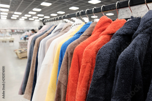 Bathrobes hang on hangers in the store red, blue, black colors. Clothing for home use.