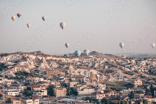Landscape with a lot of hot air balloons in the sky over the city. Famous Turkish region Cappadocia with mountains and cave cities. View from below.