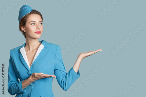 Charming stewardess on blue background. Direction sign.