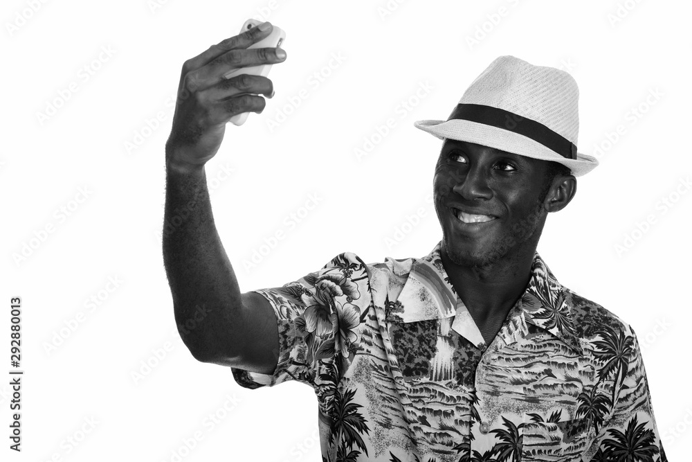 Young happy black African man smiling and taking selfie with mobile phone Young happy black African man smiling and taking selfie with mobile phone