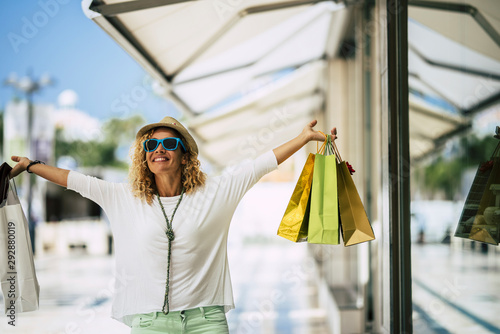 one woman walking on the street of the city with some stores - go shopping with a lot of bag on her hands - shopper lifestyle photo