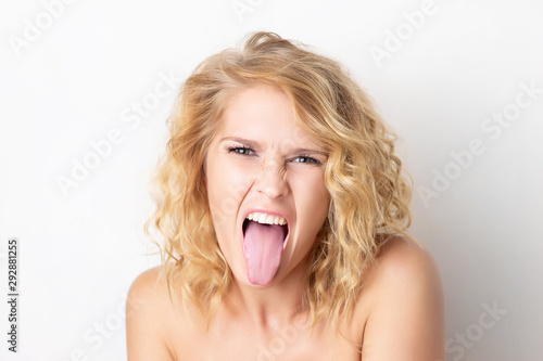 Closeup portrait of a woman with foolish grimace showing tongue isolated at white background. Concepy of joy and careless lifestyle. Funny emotion.