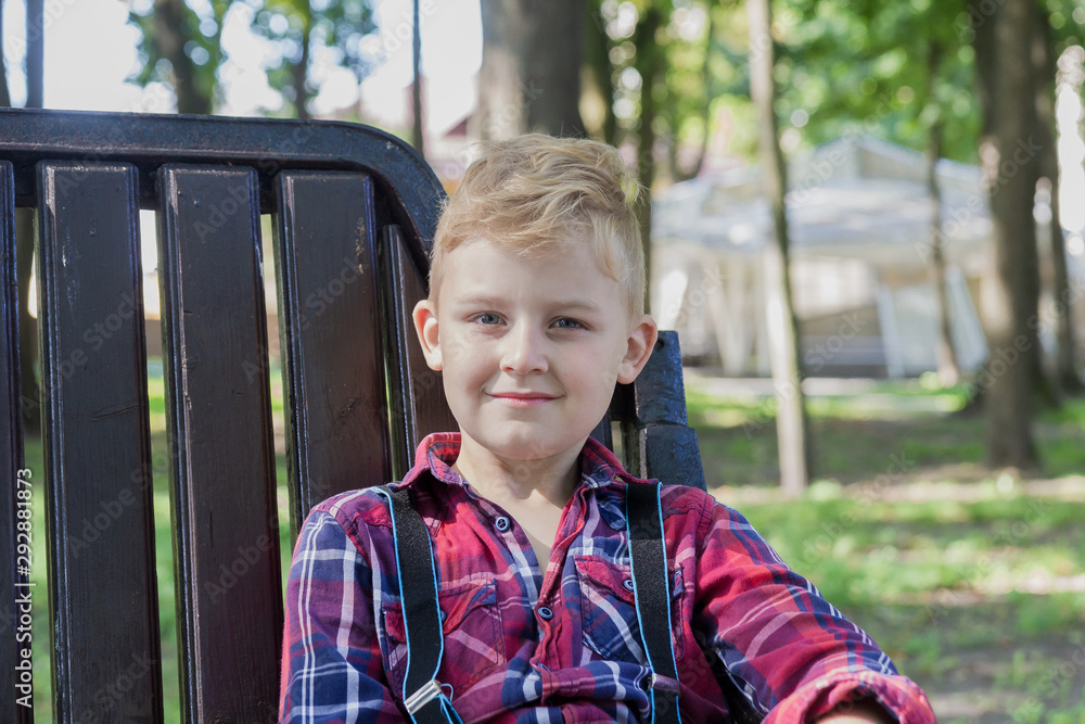 Beautiful boy 7 years old sits on a bench in the park. Beautiful boy 7 years old sits on a bench in the park.