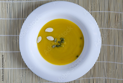 pumpkin soup in a white plate pumpkin seeds light background