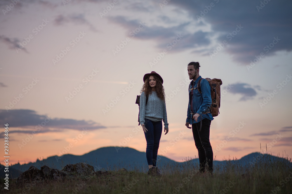 Young tourist couple travellers with backpacks hiking in nature at dusk. Young tourist couple travellers with backpacks hiking in nature at dusk.