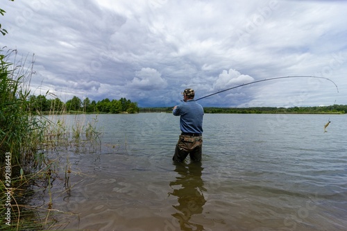 fisherman standing in the lake and catching the fish during cloudy day