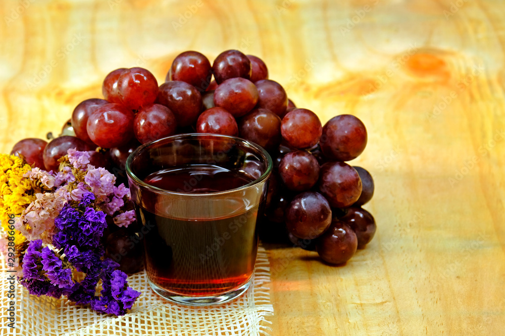 Fresh organic grape juice in a glass with bunch of grapes and dried flowers on light wooden table. Fresh organic grape juice in a glass with bunch of grapes and dried flowers on light wooden table.