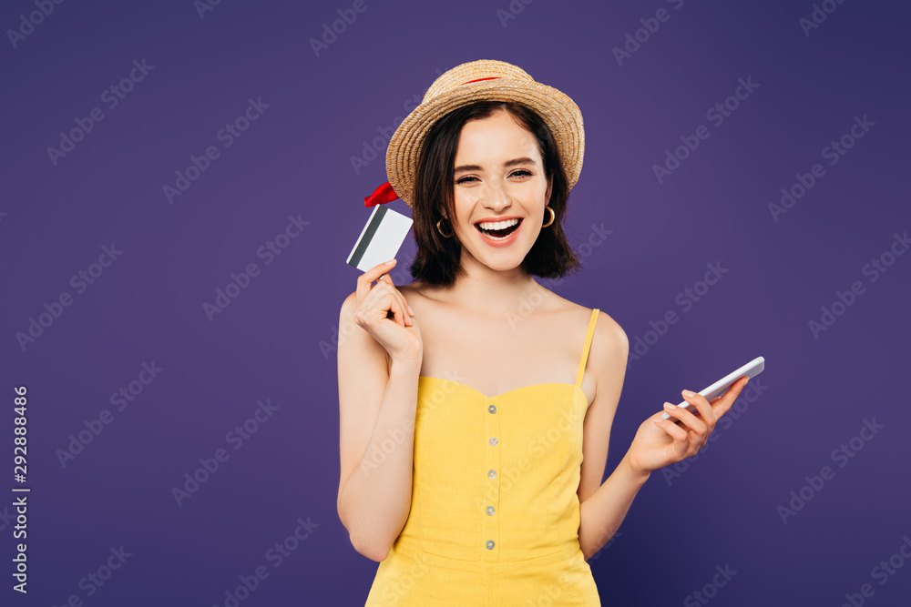 smiling girl in straw hat holding smartphone and credit card isolated on purple smiling girl in straw hat holding smartphone and credit card isolated on purple