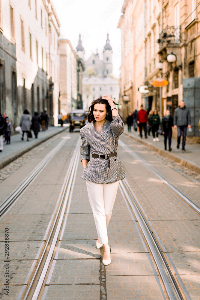 Beautiful woman standing on the tram road and enjoying the walk in the city