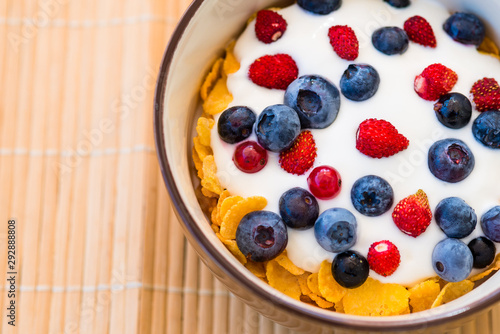Healthy breakfast - Cornflakes with fresh bilberries, raspberries and yogurt