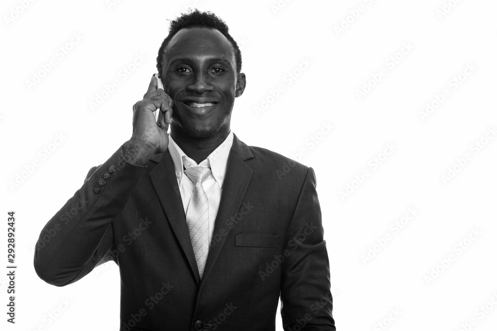 Young happy African businessman smiling while talking on mobile phone Young happy African businessman smiling while talking on mobile phone